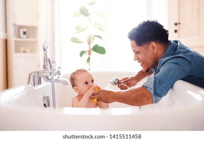 Father washing small toddler son in a bathroom indoors at home.