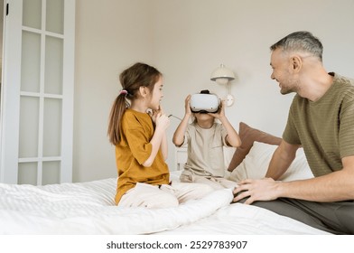 A father is watching his two daughters as they play with a VR headset. They are all smiling and enjoying their time together. This is a great example of a family bonding over technology. - Powered by Shutterstock