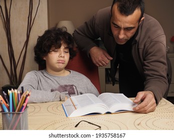 A Father Who Has No Patience With His Son Who Does Not Want To Study Child Studying With Books In The Dining Room With A Caucasian Male Adult, They  Are Not Happy. 