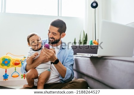 Father working with his baby boy in home office with laptop. Work from home concept
