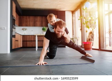Father working out, doing single arm plank with his jolly infant baby riding on his neck. Stay at home apartment. Family quarantine, domestic life in self-isolation. Sunset light  - Shutterstock ID 1690523599