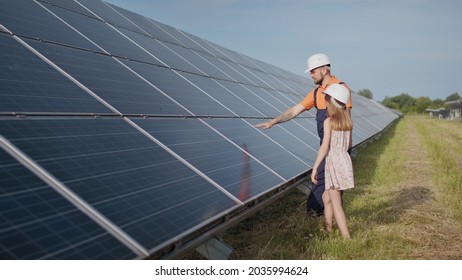 A father working in a solar power plant tells his daughter about his work, shows green energy, solar panels. Shooting at a solar power plant. Preservation of our planet, global warming - Powered by Shutterstock