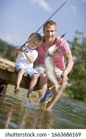 Father And Young Boy On Jetty Fishing