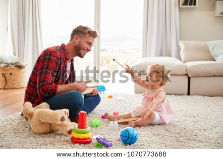 Father and young daughter playing toy instruments at home
