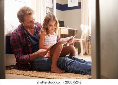 Father and young daughter reading together