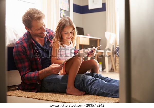 Father and young\
daughter reading\
together