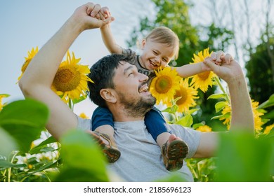 A father with a young son in a field of sunflowers during the golden hour. Dad and son are active in nature. The family walks through the summer field. Happy Father's Day - Shutterstock ID 2185696123