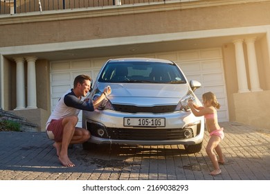 Fatherhood and childhood. Shot of a father and daughter having fun while washing a car. - Powered by Shutterstock