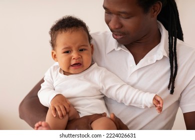 Fatherhood Concept. Caring Father Holding Little Crying Black Baby On Hands, Loving African American Dad Comforting His Sad Infant Child While They Bonding Together At Home, Closeup SHot