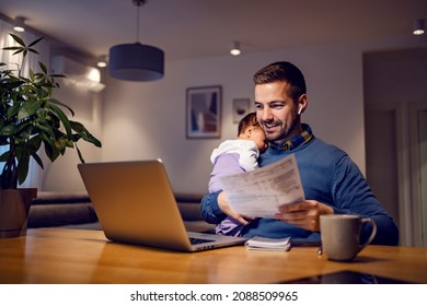 Fatherhood and remote business. A happy young dad works from home holds his sleepy baby girl in his hands, goes through paperwork and has an online meeting on his laptop with his colleagues.