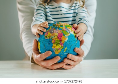 Father's and daughter's hands holding Earth globe puzzle on white wooden background. Abstract teamwork family concept.   - Powered by Shutterstock