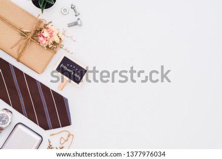 Father's day background concept. Beautiful small handmade DIY gift box (package), father's necktie, gentleman accessories and small blackboard with Happu Father's day text on white background.