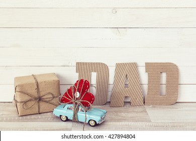 Fathers Day Background With Miniature Blue Toy Car Carrying A Heart On White Painted Planks. Happy Fathers Day Concept.
