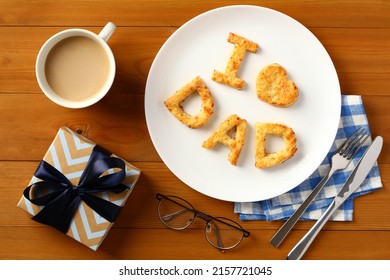 Fathers day Brunch with homemade pastry I love Dad, gift box, cup of coffee, cutlery on wooden table.