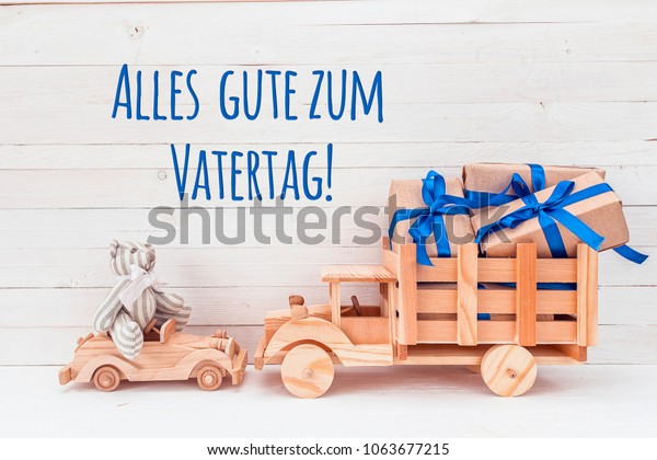 Father\'s Day card. Wooden car with toy\
bear and wooden truck with gifts. German greeting \