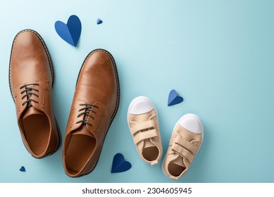 Father's Day celebration with little son. Top view of dad's leather shoes, son's sneakers, and hearts on pastel blue background with empty space - Powered by Shutterstock