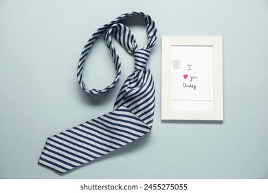 Father's day celebration. Photo frame with phrase I Love You Daddy and necktie on grey background, flat lay - Powered by Shutterstock