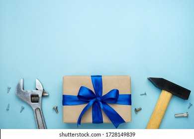 Father's day composition. Gift box wrapped in kraft paper with blue ribbon bow and hand tools on blue background. Top view flat lay with free space for text. Greeting card for Men's day or Labor day.  - Powered by Shutterstock