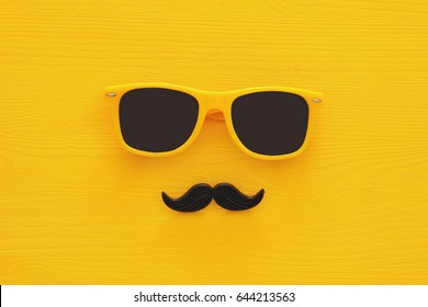 Father's day concept. Hipster yellow sunglasses and funny moustache on wooden background