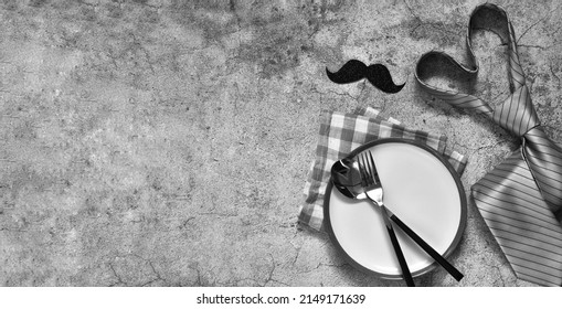 Fathers Day Concept. Table Setting - Plate, Napkin, Cutlery And Funny Mustache, Tie On Grey Concrete Table. Top View. Flat Lay Composition. Banner With Copy Space.