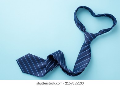 Father's Day concept. Top view photo of heart shaped blue necktie on isolated pastel blue background with copyspace