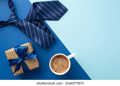 Father's Day concept. Top view photo of polka dot giftbox with blue silk ribbon bow cup of coffee and blue necktie on bicolor blue background with copyspace - Powered by Shutterstock