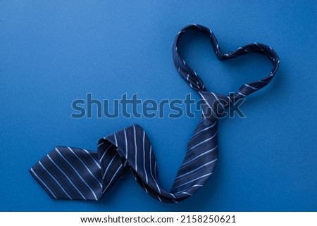 Father's Day concept. Top view photo of heart shaped blue necktie on isolated blue background