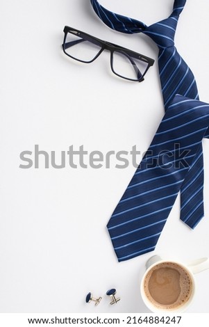 Father's Day concept. Top view vertical photo of blue tie cufflinks glasses and cup of coffee on isolated white background with empty space
