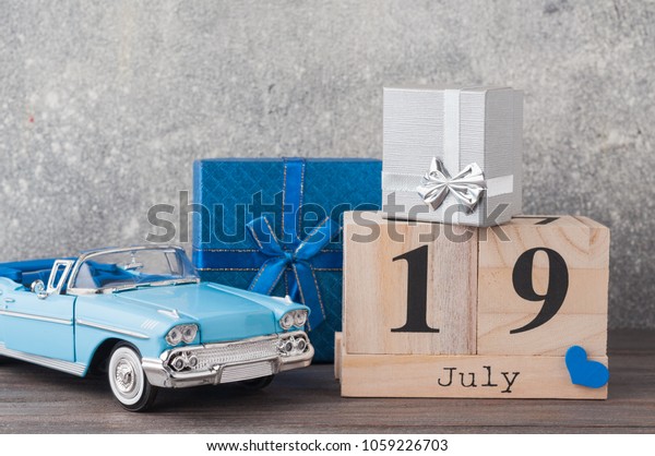 Father\'s day concept. A toy car with gifts, heart,\
19th of July on wooden background. Copy space for Fathers day\
greeting card.