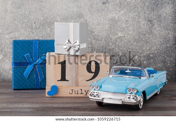 Father\'s day concept. A toy car with gifts, heart,\
19th of July on wooden background. Copy space for Fathers day\
greeting card.