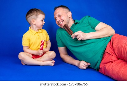 Father's day. Dad with his son eating ice cream and having fun on a blue background in colorful clothes - Powered by Shutterstock