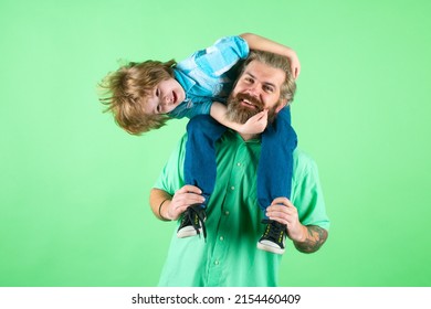 Fathers Day. Father Giving Piggyback Ride To His Son Against A Green Studio Background. Happy Family. Cute Child Boy Hugs His Daddy.
