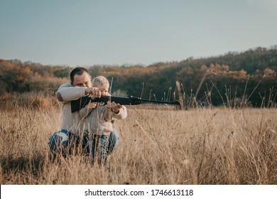 Father's Day. Father With Gun Showing Something To Son While Hunting On A Nature. Happy Family, Fathers Day And Local Summer Vacation.