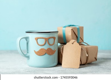 father's day gift concept. blue mug with mustache and glasses and gift boxes on a blue background - Shutterstock ID 1745593046