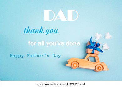 Father's Day Greeting Message With Wooden Toy Car With A Gift Box On The Roof On Blue Background. Fathers Day Background.