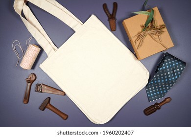 Father's Day Or Masculine Birthday Canvas Tote Bag Flatlay Styled With Gift, Chocolate Tool Set And Tie. White Product Mock Up With Negative Copy Space For Your Text Or Design Here.