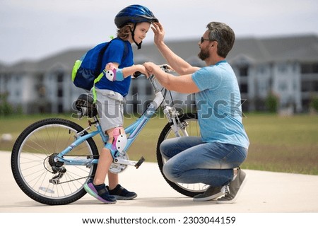 Fathers day and summer family weekend. Father helping his son to wear a cycling helmet. Child in safety helmet. Father support and helping son. Fathers day concept. Father and son friends. Child care.
