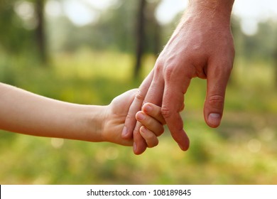 father's hand lead his child son in summer forest nature outdoor, trust family concept
