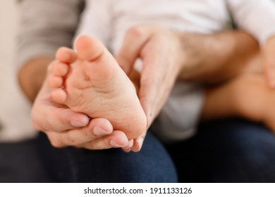 Father's hands carefully keeping baby's foot with tenderness