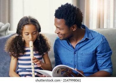 Fathers Are Often The First Teachers In Their Childrens Lives. Shot Of A Young Father Teaching His Daughter How To Play The Recorder At Home.