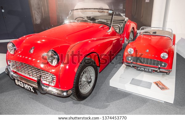 Fathers\
and sons\' car passion. British Motor Museum, Warwickshire / UK - \
03 02 2019: 1960 Triumph TR3 half-scale pedal car with the\
original. Dad and son could drive the same\
car.