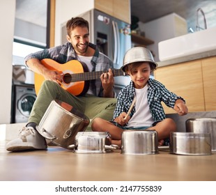 Its a father-son collaboration. Shot of a happy father accompanying his young son on the guitar while he drums on a set of cooking pots. - Powered by Shutterstock