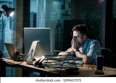 Fatigue Man In Shirt Rubbing Face While Watching Computer Totally Exhausted Working Late At Night. 