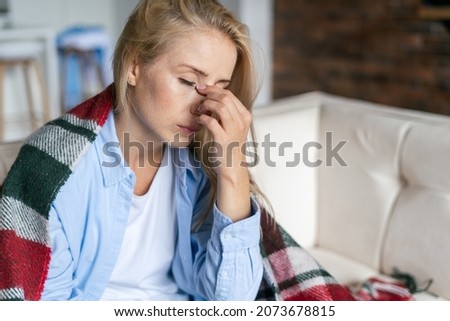 Fatigue and upset woman touching nose bridge feeling eye strain or headache, trying to relieve pain. Sick and exhausted female spending day at home. Depressed lady feeling weary dizzy