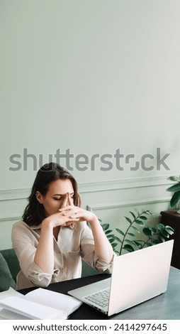Fatigued and Dismal Young Woman Struggling with Overexertion While Staring at Computer. Weary Young Woman in Distress: Overexerted and Gloomily Contemplating at Her Computer.