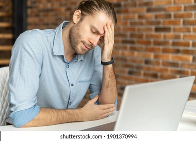 Fatigued hipster using laptop for working, a guy tired and burnout, holding head and feels headache, migraine sitting at the desk in modern office with eyes closed. Overwork concept - Shutterstock ID 1901370994