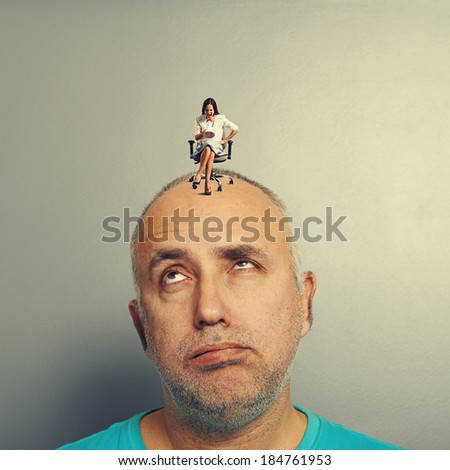 fatigued man and small angry woman on his head over grey background