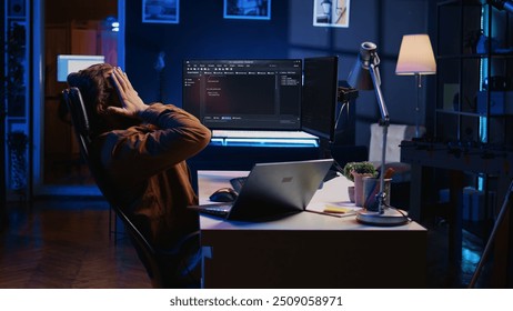 Fatigued software programmer working overnight at home, taking break from coding to stretch at desk chair. Overworked IT professional feeling exhausted, pausing tasks to rest, camera B - Powered by Shutterstock