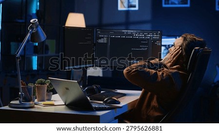 Fatigued software programmer working overnight at home, taking break from coding to stretch at desk chair. Overworked IT professional feeling exhausted, pausing tasks to rest, camera A.