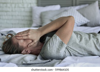 Fatigued woman lying at bedstead